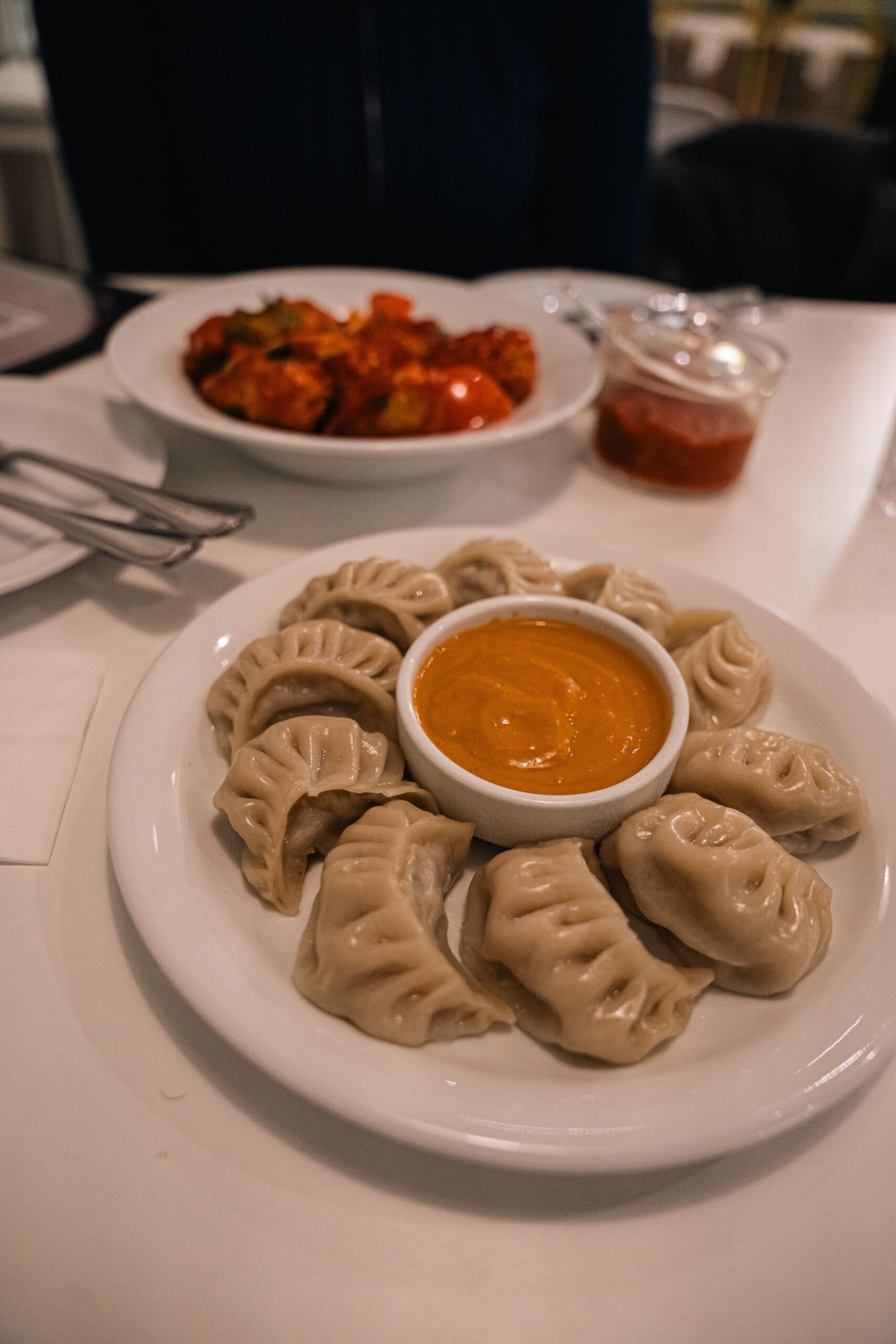 A close-up of steamed momos served with a spicy dipping sauce, perfect for food presentations.